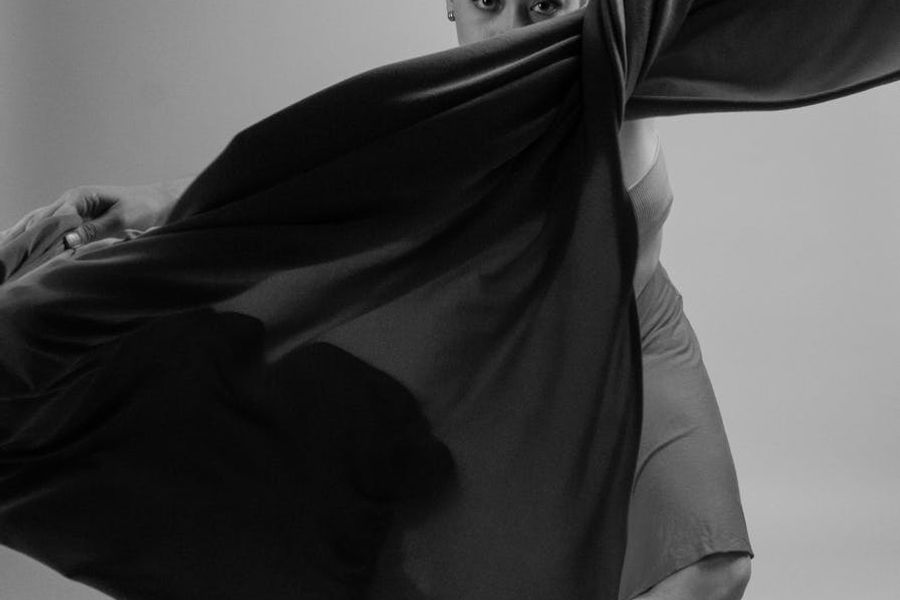 Person doing rhythmic movements in a minimalist dark studio.